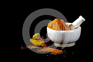 Turmeric powder in mortar with pestle and roots or barks
