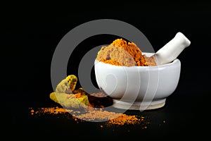 Turmeric powder in mortar with pestle and roots or barks