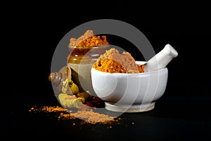 Turmeric powder in mortar with pestle and roots or barks