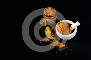 Turmeric powder in mortar with pestle and roots or barks