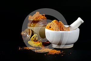 Turmeric powder in mortar with pestle and roots or barks