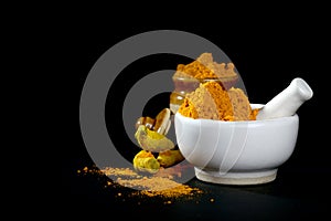 Turmeric powder in mortar with pestle and roots or barks