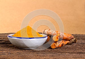 Turmeric powder and roots curcumin on wooden plate