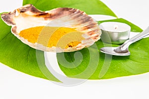Turmeric powder in seashell and green leaf with spoon isolated o