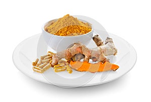 Turmeric powder and turmeric capsules in a plate on white background