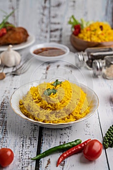 Turmeric rice in a white plate with spices on a white wooden floor