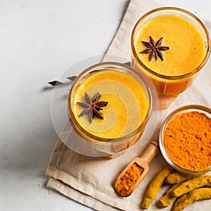 Turmeric smoothie in glass with ingredients,  powder, ginger and spice on white