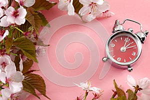 Turn clocks on hour ahead, star of daylight savings time and reminder to spring forward concept with alarm clock on pink