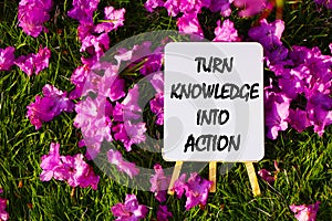 Turn knowledge into action On background of pink flowers and green grass.