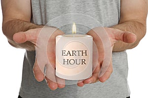 Turn off lights for Earth hour. Man holding burning candle on white background, closeup