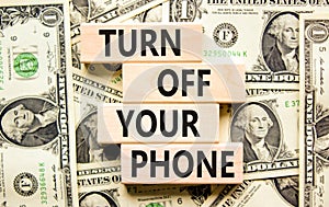 Turn off your phone symbol. Concept words Turn off your phone on wooden blocks. Beautiful background from dollar bills. Business,