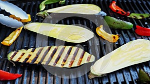 Turn over eggplant with vegetables grill on a cast iron barbecue. Close up. Slow motion