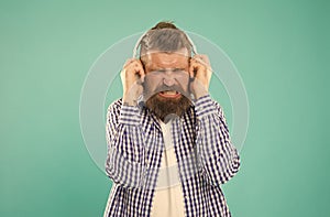 turn the sound down. unhappy hipster listening ebook. bearded man with loud sound in earphones.