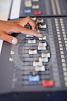 Turn up the tunes. Cropped close-up image of a hand moving a slider on a mixing desk.