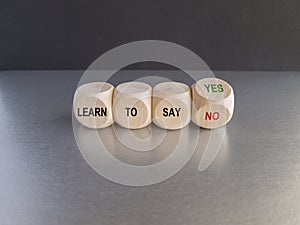 Turned a cube and changes the expression learn to say yes to learn to say no. Beautiful grey table black background.