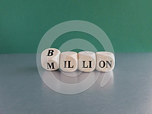 Turned a cube and changes the word Million to Billion. Beautiful green background, grey table. Business concept