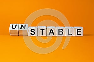 Turned cubes and changed the word `unstable` to `stable` or vice versa. Beautiful orange background. Business concept. Copy sp