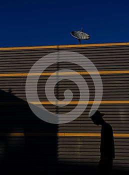 A Turned off Antenna against a Dark Blue Sky and a Sad Boy Silhouette Walking to a No Reception Home.