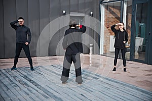 Turned person and tai chi students holding fist before forehead