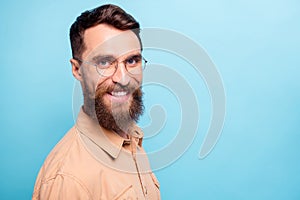 Turned photo of charming man looking with beaming smile wearing brown shirt  over blue background