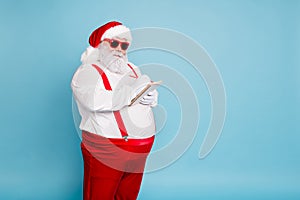 Turned photo of funny funky fat santa claus in modern eyewear with big belly abdomen write with pencil in note book make