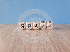 Turned a wooden cube and changes the German word spass to sparen . Beautiful wooden table blue background. photo