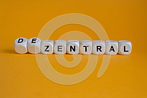 Turned wooden cube and changes the German word \'zentral\' (centralized) to \'dezentral\'