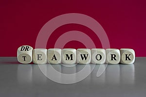 Turned a wooden cube and changes the word teamwork to dreamwork. Beautiful red background, grey table. Concept of well-coordinated photo