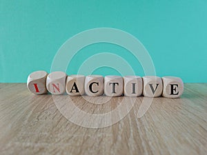 Turned wooden cubes and changed the concept word Inactive to Active. Beautiful wooden table blue background, copy space. Business