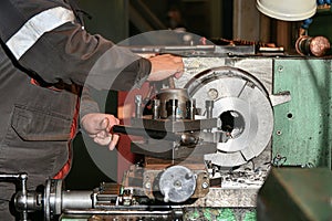 The turner removes excess chips with a hook when processing metal on a lathe