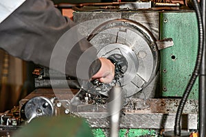 The turner removes excess chips with a hook when processing metal on a lathe