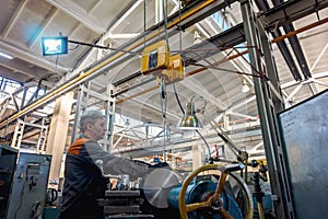 Turner worker manages the metalworking process of mechanical cutting on a lathe