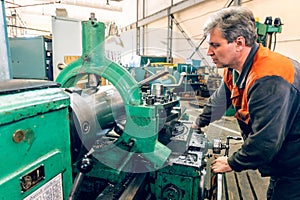 Turner worker manages the metalworking process of mechanical cutting on a lathe