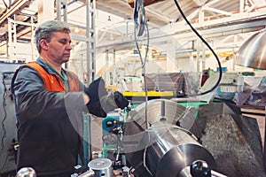 Turner worker manages the metalworking process of mechanical cutting on a lathe