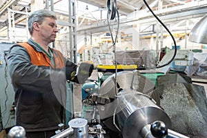 Turner worker manages the metalworking process of mechanical cutting on a lathe