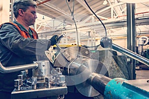 Turner worker manages the metalworking process of mechanical cutting on a lathe