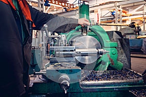 Turner worker manages the metalworking process of mechanical cutting on a lathe