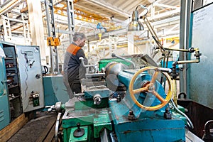 Turner worker manages the metalworking process of mechanical cutting on a lathe