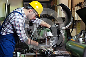 Turner worker is working on a lathe machine in a factory.