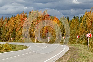 Turning the asphalt road. Autumn landscape, road signs, gloomy sky.