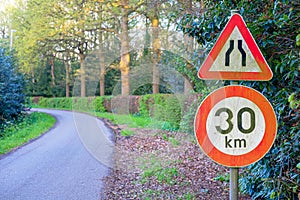 Turning countryside road with speed limit and danger sign