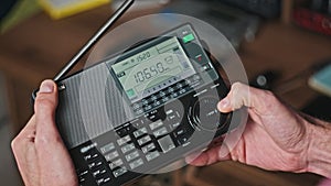 Turning Modern Portable Radio With Digital LCD Frequency Scale in Male Hands