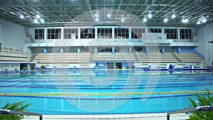 Turning off lights in empty pool with clear water and dividers track for swimming. Blue water in swimming pool. Night