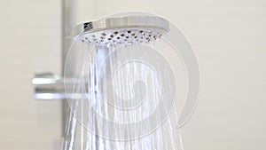 turning on and off shower head in bathroom, water flow in front of camera, falling drops in slow motion. Close-up