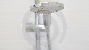 turning on and off shower head in bathroom, water flow in front of camera, falling drops in slow motion. Side view