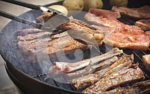 Turning tasty spiced meat being cooked on a braai or barbeque