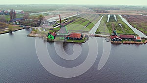 Turning windmill of Zaans Schans museum by the water channel, panoramic drone view, Netherlands