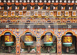 Turning wooden prayer wheels mantra in Bhutan with traditional writing mantra which sounds as Om mani padme hum, literally means ` photo