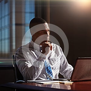 he turns to his intuition when making tough decisions. a young man contemplating while using his laptop.