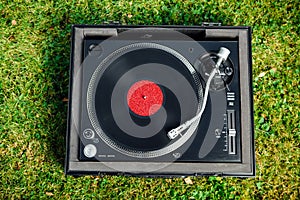 Turntable with LP vinyl record on grass background